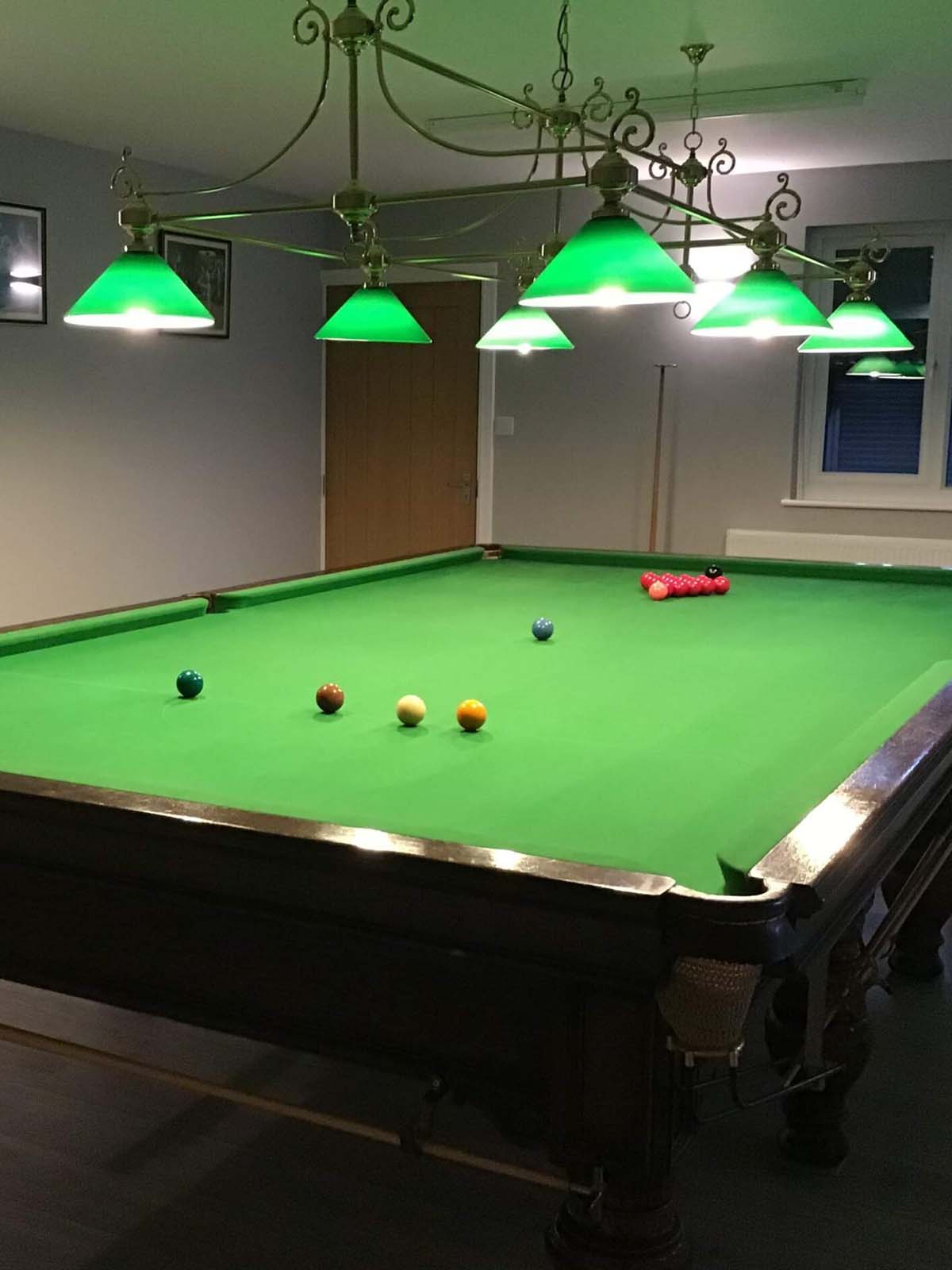 pool table with matching green overhead lighting