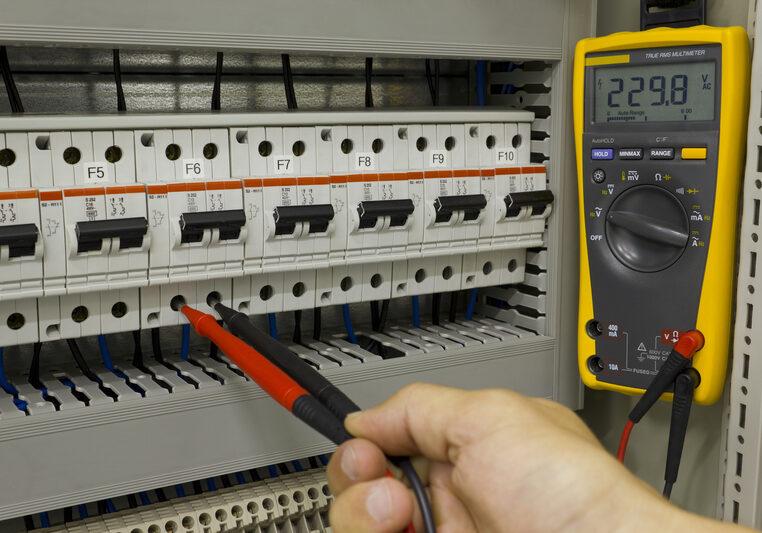 Electrical engineer at work. Electrical engineer measuring voltage on a miniature circuit breaker.